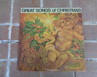 May include: Vintage vinyl record album cover titled "Great Songs of Christmas." The cover features a golden cherub with wings, surrounded by holly and other festive foliage. The background is a warm, ornate design.