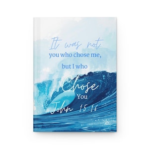 May include: A journal with a watercolor design of a wave in shades of blue. The cover features the text "It was not you who chose me, but I who chose you, John 15:16" in a script font.