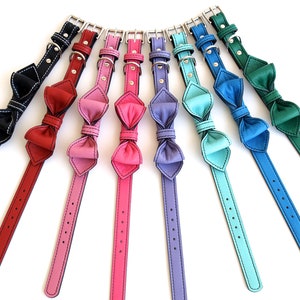 May include: A set of ten leather dog collars with bow ties in various colours, including black, red, pink, purple, blue, teal, and green.