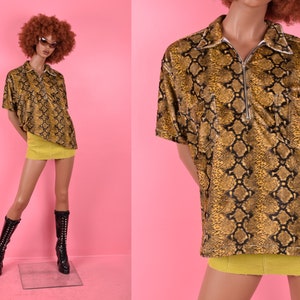 May include: A short-sleeved, collared shirt with a snake skin pattern. The shirt has a zipper closure and a pocket on the left side. The shirt is yellow and brown.