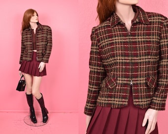 May include: A vintage plaid jacket with a zipper closure, paired with a matching pleated skirt. The jacket features a brown, red, and gold checkered pattern. The outfit is completed with black boots and a small black handbag.