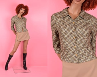 Puede incluir: Una camisa de cuadros marrones y verdes con cuello y mangas largas. La camisa tiene un cierre de botones en la parte delantera y una silueta ajustada.