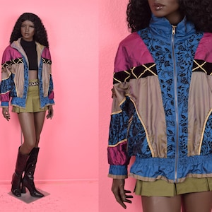 May include: A vintage colour-block jacket with a zip-up front. The jacket features panels of blue floral print, pink, tan, and black velvet with gold trim. The jacket is paired with a black top, a khaki pleated skirt, and black knee-high boots.