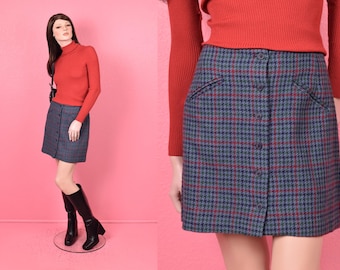 May include: A blue and red plaid mini skirt with a button front closure. The skirt is made of a wool blend fabric.