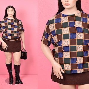May include: A brown and blue checkered top with a brown mini skirt. The top has a short sleeve and a round neckline.