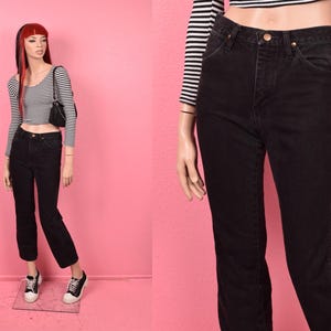 以下が含まれることがあります： ハイウエストとストレートレッグの黒いデニムジーンズ。ジーンズは、黒と白のストライプの長袖クロップトップと組み合わせています。マネキンは、黒と白のスニーカーと小さな黒いハンドバッグを履いています。