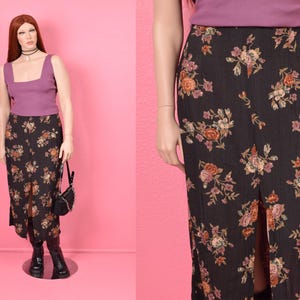 Puede incluir: Una falda midi negra con estampado floral. La falda tiene una abertura en la parte delantera y está hecha de una tela suave y fluida.