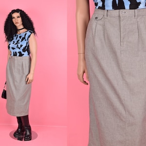 May include: A gray midi skirt with a straight silhouette and a subtle texture. The skirt has a high waist and a zipper closure in the back.