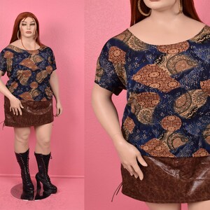 May include: A blue and brown patterned top with a scoop neck and short sleeves. The top is paired with a brown faux leather skirt.