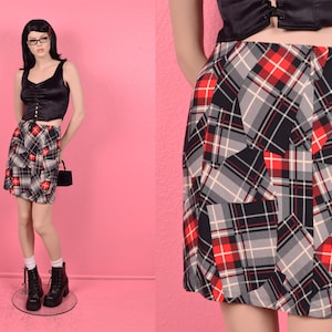 May include: A black and white plaid skirt with red and white accents. The skirt is a mini length and has a straight silhouette.