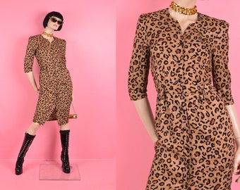 May include: A brown and black leopard print midi dress with a button-up front and 3/4 sleeves. The dress is fitted and has a slightly flared skirt.