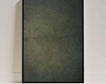 May include: A framed art print featuring a textured, dark green abstract design. The artwork is enclosed in a black frame and leans against a white wall and baseboard.