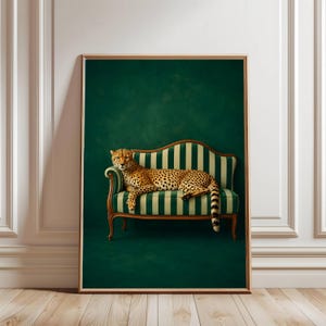 Könnte beinhalten: Gerahmter Kunstdruck mit einem Geparden, der sich auf einem grün-cremefarbenen Sofa mit Streifen ausruht. Der Gepard hat ein geflecktes Fell, und der Hintergrund ist dunkelgrün. Das Sofa hat Holzbeine und Armlehnen.