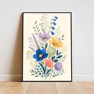 Puede incluir: Impresión artística enmarcada que presenta un arreglo floral en acuarela. El ramo incluye flores azules, moradas, amarillas y rosas con follaje verde sobre un fondo crema. La obra de arte se muestra en un marco negro.