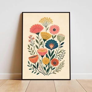 Puede incluir: Un cuadro enmarcado con una impresión floral que presenta un ramo de flores estilizadas. Las flores son de color rosa, naranja, amarillo y azul, con hojas verdes. El fondo es beige claro y el marco es negro.