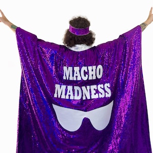 May include: A purple sequined cape with the words "MACHO MADNESS" in white block letters. The cape features a white sunglasses design below the text. A matching purple sequined headband is also visible.