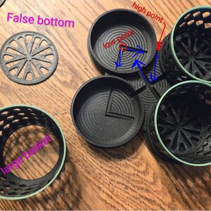 May include: A black 3D printed organizer set featuring three cylindrical baskets with a lattice pattern, three circular bases with concentric rings, and three removable false bottoms with a radial spoke design, labeled with text.