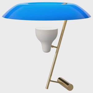 Puede incluir: Una lámpara de mesa moderna con una pantalla azul brillante y redondeada y una lámpara blanca en forma de cono invertido. La lámpara tiene un soporte dorado en ángulo y una base cilíndrica. El diseño es minimalista y contemporáneo.