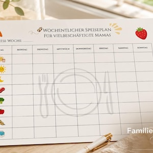 May include: A white A4 weekly meal planner sheet titled WOCHENTLICHER SPEISEPLAN FÜR VIELBESCHÄFTIGTE MAMAS. The grid features columns for days of the week, rows with small food and weather icons, and a faint central illustration of a plate, fork, and knife.
