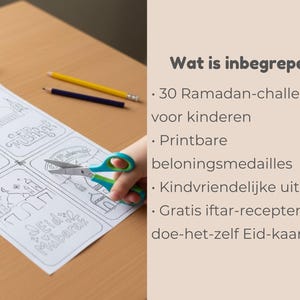 May include: A white paper with line drawings and the text "Eid Mubarak" is being cut with blue and green scissors. The paper has drawings of mosques and people. Pencils and an eraser are on the wooden surface.