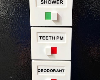 May include: A vertical stack of five white rectangular plastic task trackers with sliding switches. Each tracker features black text labels: WORKOUT, SHOWER, TEETH PM, DEODORANT, and MELATONIN. The switches reveal green or red color indicators.