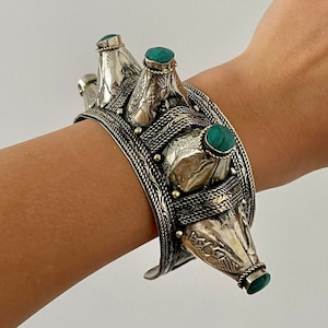 Może przedstawiać: Srebrna bransoletka o unikalnym wzorze z wieloma elementami w kształcie łzy ozdobionymi turkusowymi kamieniami.