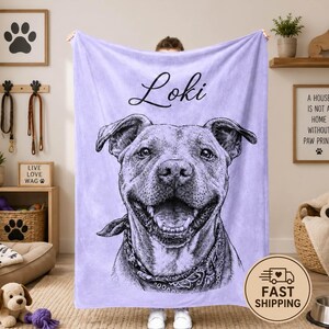Puede incluir: Una manta de forro polar de color morado claro con un boceto en blanco y negro de un perro pitbull que lleva un pa&ntilde;uelo. El nombre Loki est&aacute; impreso en letra cursiva negra sobre la cabeza del perro. La manta tiene una textura suave.