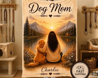 Puede incluir: Una manta de forro polar rectangular con un paisaje impreso de una puesta de sol sobre un lago con montañas y pinos. El texto "Dog Mom" aparece en la parte superior y el nombre "Charlie" está impreso en la parte inferior. La imagen muestra a una persona y un perro.
