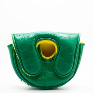 May include: A green golf putter cover with a yellow interior. The cover has a textured surface with a repeating pattern and the word "Masters" is visible. The cover is designed to protect a golf club.
