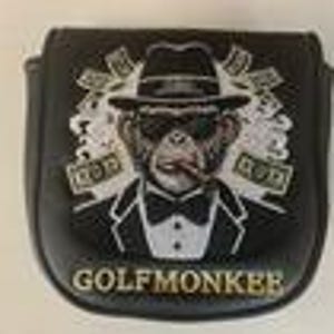 May include: A black golf putter headcover featuring a graphic of a monkey wearing a tuxedo, fedora, and sunglasses while smoking a cigar. The design includes floating dollar bills and the text GOLFMONKEE printed in gold at the bottom.