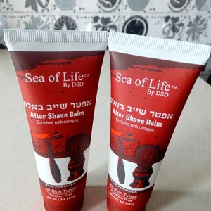 Peut inclure: Deux tubes rouges de baume après-rasage "Sea of Life". Les tubes ont des dessus blancs et présentent du texte en anglais et en hébreu. Chaque tube a une illustration d'un rasoir et d'un blaireau. Le baume est pour tous types de peau et sans parabène.