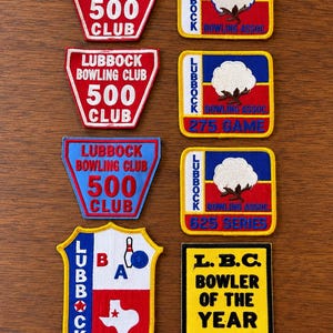 Op de afbeelding: Een verzameling van acht geborduurde patches met thema's van de Lubbock Bowling Club en Association. De patches bevatten rode, blauwe, gele en witte ontwerpen met teksten zoals 500 CLUB, 275 GAME, 625 SERIES en L.B.C. BOWLER OF THE YEAR 80-81.