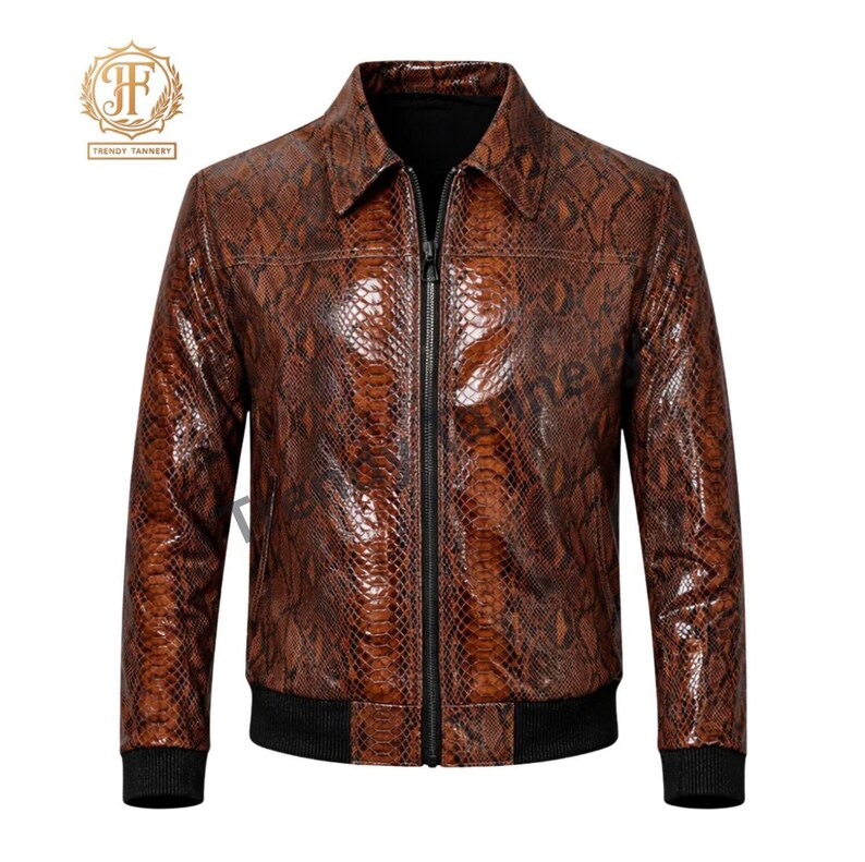May include: A brown jacket featuring a snakeskin pattern, a pointed collar, and a full-length black front zipper. The garment includes black ribbed cuffs and a black ribbed hem, with a logo in the upper left corner reading Trendy Tannery.