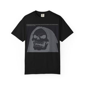 Puede incluir: Camiseta negra con un diseño de calavera pixelada con capucha en tonos grises y blancos. Texto encima de la calavera. La camiseta tiene cuello redondo y mangas cortas.