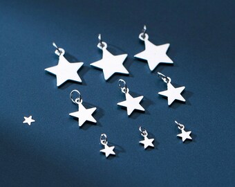May include: A collection of silver star charms of varying sizes, arranged on a blue background. The charms are all in the shape of a five-pointed star and have a shiny, metallic finish.