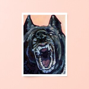 May include: An art print featuring a close-up of a snarling black dog with exposed teeth and a wide-open mouth. The dog's fur is dark, and the background is a soft peach color. The artwork is framed in white.