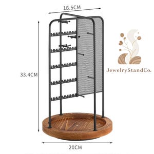 May include: A black metal jewelry display stand with a wooden base. The stand is 13.1 inches tall, 7.3 inches wide, and the base is 7.9 inches in diameter. It features multiple earring slots and a mesh panel for hanging necklaces. The base is made of light brown wood.