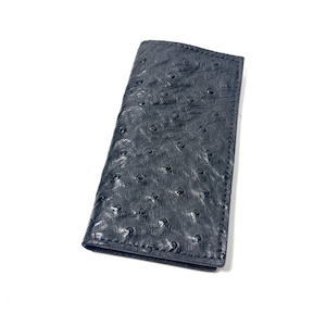 May include: A rectangular navy blue wallet featuring a textured surface with a pattern of small, raised circular bumps. The wallet is constructed with visible stitching along the edges and has a slim, elongated profile with a folded design.