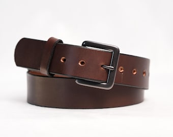 May include: A dark brown leather belt featuring a smooth finish and a rectangular matte black metal buckle. The belt includes a matching leather keeper loop and a series of evenly spaced circular holes along the strap for adjustable fastening.