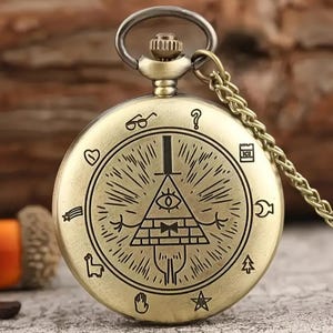 May include: A round, antique-gold colored pocket watch with a chain. The front cover features an engraved pyramid with a single eye, a bowtie, and arms, surrounded by small symbols including glasses, a question mark, a heart, a star, and a hand.