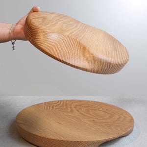 Puede incluir: Dos fuentes de madera para servir. Una se sostiene en alto, mostrando la parte inferior, y la otra descansa sobre una superficie. Ambas son de forma ovalada con un acabado de veta de madera natural. La fuente inferior tiene un asa curvada.