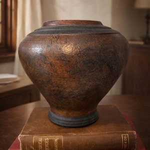 May include: A white ceramic mug with a black handle and the text "But First, Coffee" in a black, handwritten-style font. The mug is on a white surface.