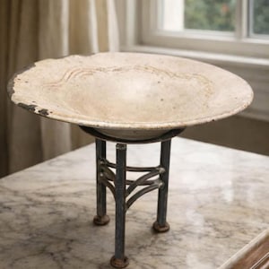 May include: A white ceramic mug with a black handle and the text "But First, Coffee" in a bold, black font. The mug is set against a blurred background, highlighting its clean design.