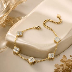 Può includere: Un bracciale a catena color oro con quattro ciondoli a forma di quadrifoglio. Ogni ciondolo a quadrifoglio è incastonato con piccole pietre trasparenti e scintillanti. Il bracciale include una sottile catena a maglie, un moschettone e una catenina di estensione.