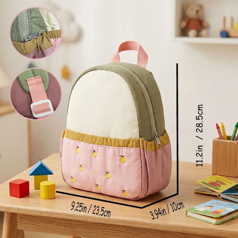 May include: A small, colorful backpack with a pink, white, and olive green design. The backpack features a pink handle and straps, and is embroidered with yellow fruit. Dimensions are 11.2 inches high, 9.25 inches wide, and 3.94 inches deep.