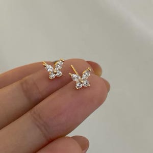 以下が含まれることがあります： 金色の蝶のスタッドピアス。各ピアスは、透明で輝く宝石が付いた蝶のデザインが特徴です。ピアスは小さく繊細で、普段使いに最適です。