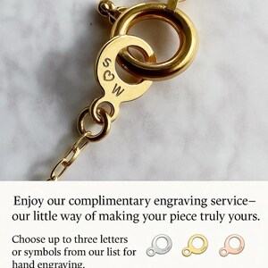 May include: Close-up of a gold necklace clasp with engraved initials "S♡W". The clasp is attached to a fine chain. The image includes text about complimentary engraving services.