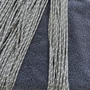 May include: A collection of multiple strands of grey cord featuring a repeating white speckled pattern. The cords are arranged in parallel vertical lines, showcasing a braided texture and a consistent diameter throughout each individual length.