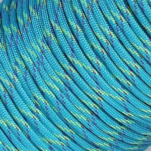 May include: A spool of braided cord featuring a vibrant turquoise base color with interwoven diagonal patterns in bright lime green and dark purple. The cord has a smooth, tightly woven texture and is coiled in parallel rows around a central core.