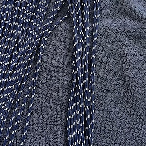 May include: A collection of multiple long, thin, braided cords in a deep navy blue color. Each cord features a repeating pattern of small, white, diagonal flecks woven throughout the length of the material, creating a consistent textured appearance.